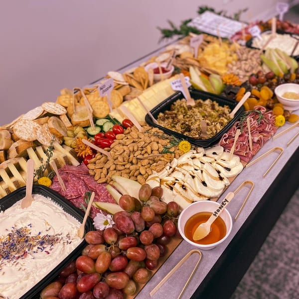 A long table filled with a Feast and Graze charcuterie spread, featuring cheeses, meats, fruits, and nuts.