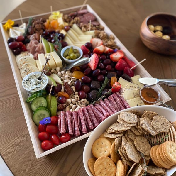 A large Feast and Graze charcuterie board with cheeses, meats, fruits, nuts, and crackers.