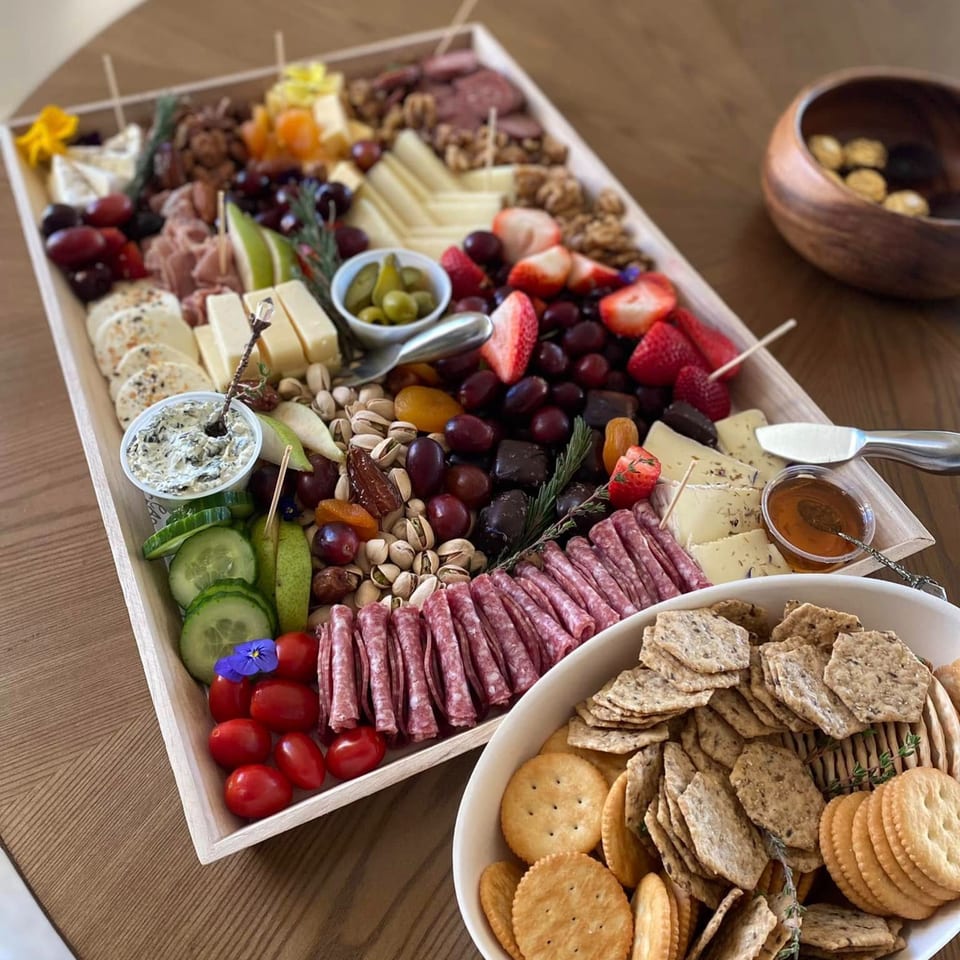 A large Feast and Graze charcuterie board with cheeses, meats, fruits, nuts, and crackers.