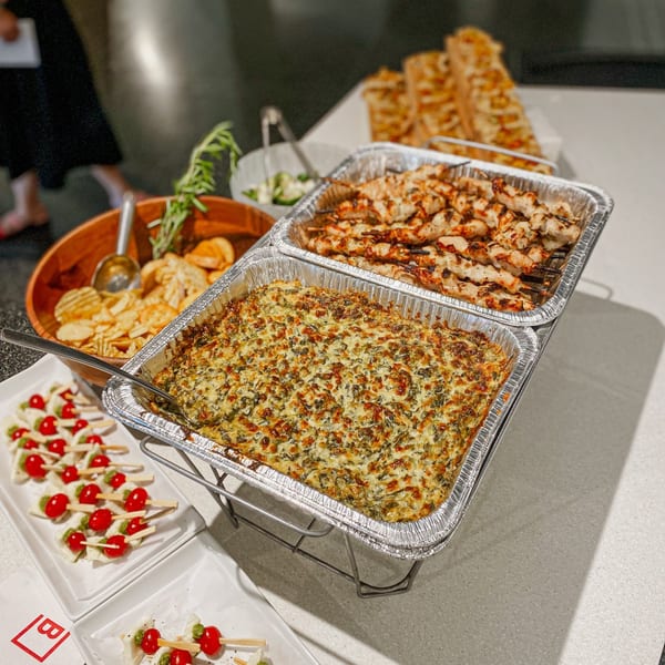 A Feast and Graze catering spread with spinach dip, chicken skewers, chips, and caprese bites.