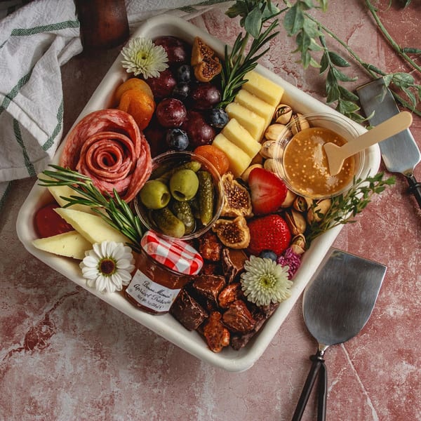 A Feast and Graze charcuterie board with meats, cheeses, fruits, nuts, and honey.