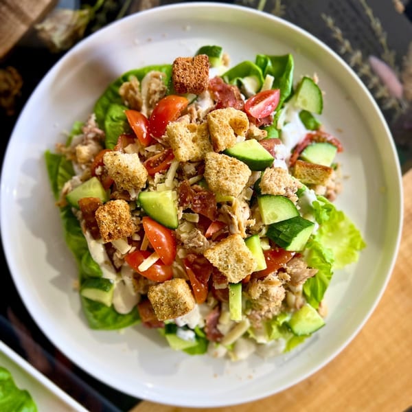 Feast and Graze cafe salad with lettuce, tomatoes, cucumbers, croutons, and chicken.